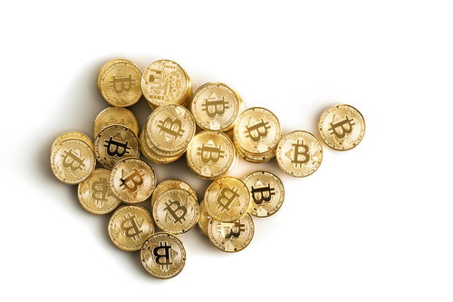 白い背景に散らばるビットコインのコイン - 暗号資産投資