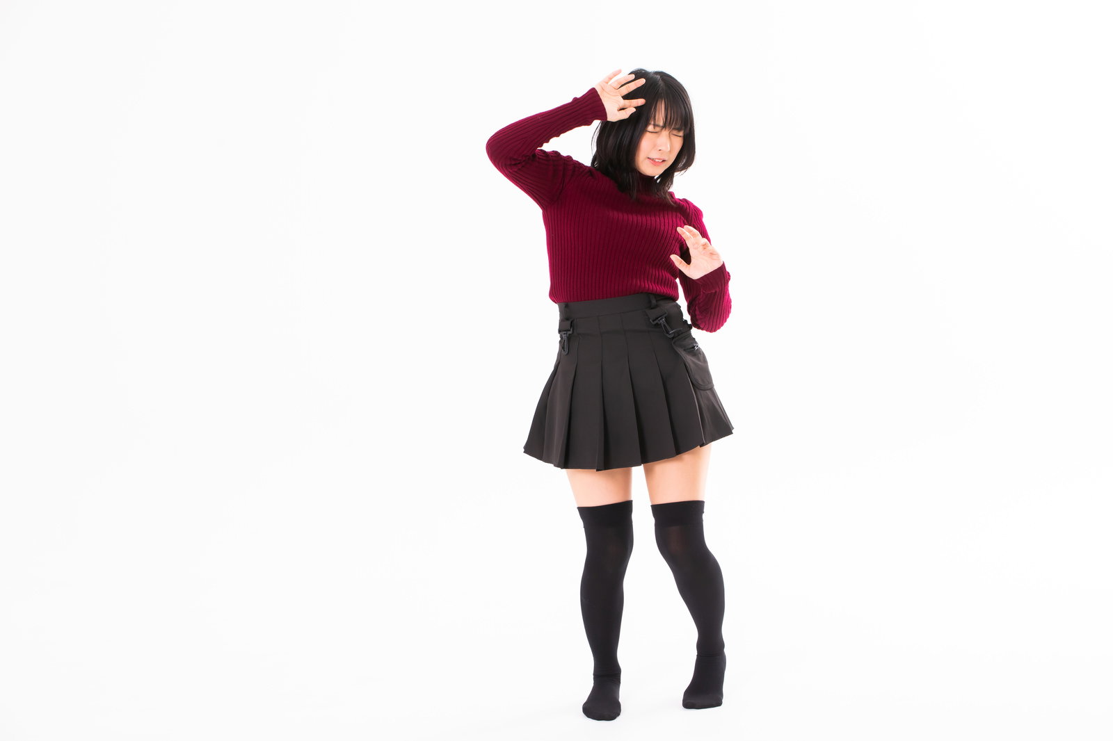 赤いトップスと黒いスカートの女性が手を額にかざして眩しさから顔を背けるポーズ［モデル：にゃるる］