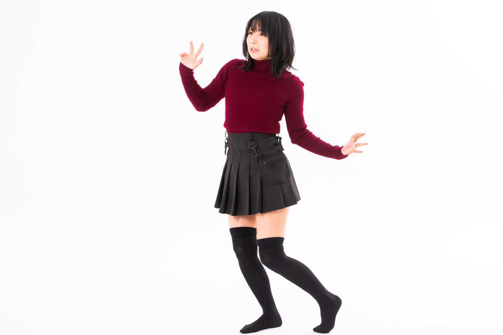赤いニットと黒いスカートを着た女性が驚いた表情で両手を広げている［モデル：にゃるる］