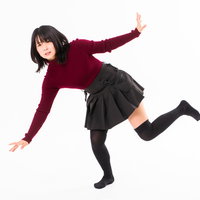 躓いてバランスを崩すエンジ色セーターの女性の写真