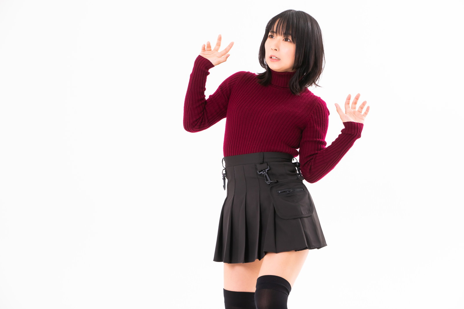 赤いセーターを着た女性が両手を前に出して驚いて後ずさりしている［モデル：にゃるる］
