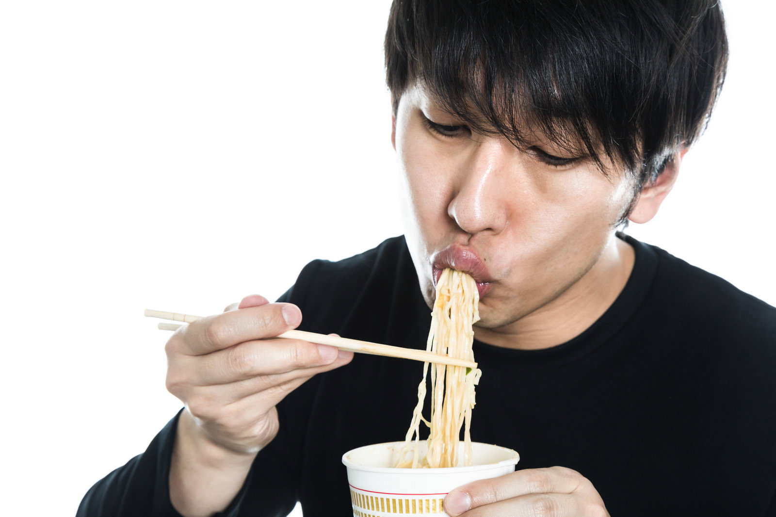 箸を使ってカップラーメンを食べている黒いTシャツの男性［モデル：大川竜弥］