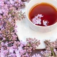 ライラックの花弁が浮かぶ紅茶のティーカップの写真