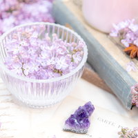 透明なガラス器に生けたライラックの花と散らばった花弁の写真