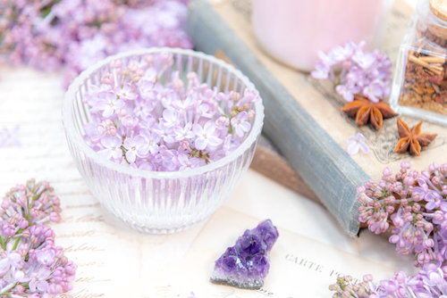 透明なガラス器に生けたライラックの花と散らばった花弁