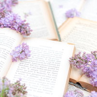 しおりの代わりに挟んだライラックと洋書、生花を使った読書シーンの写真