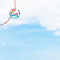 赤い紐と和柄の風鈴が揺れる爽やかな夏の一景の写真