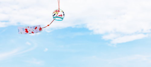 赤い紐と和柄の風鈴が揺れる爽やかな夏の一景