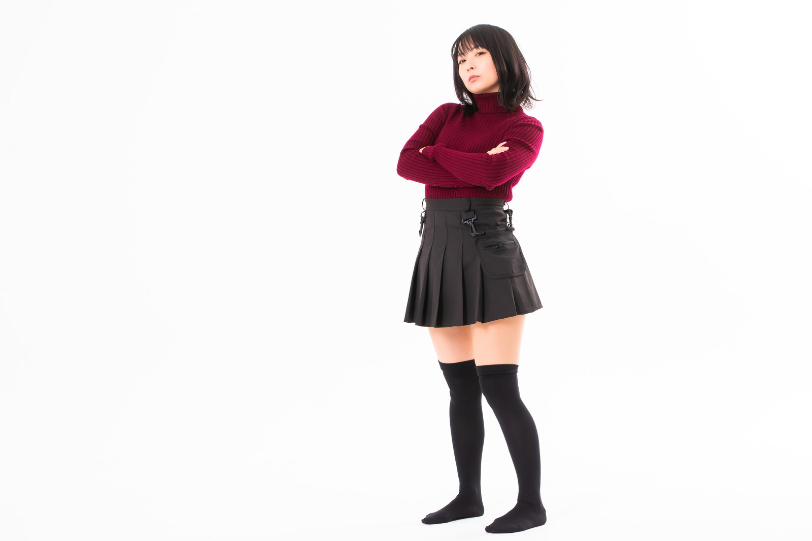 腕組みして仁王立ちする赤いトップスと黒いスカートの女性［モデル：にゃるる］