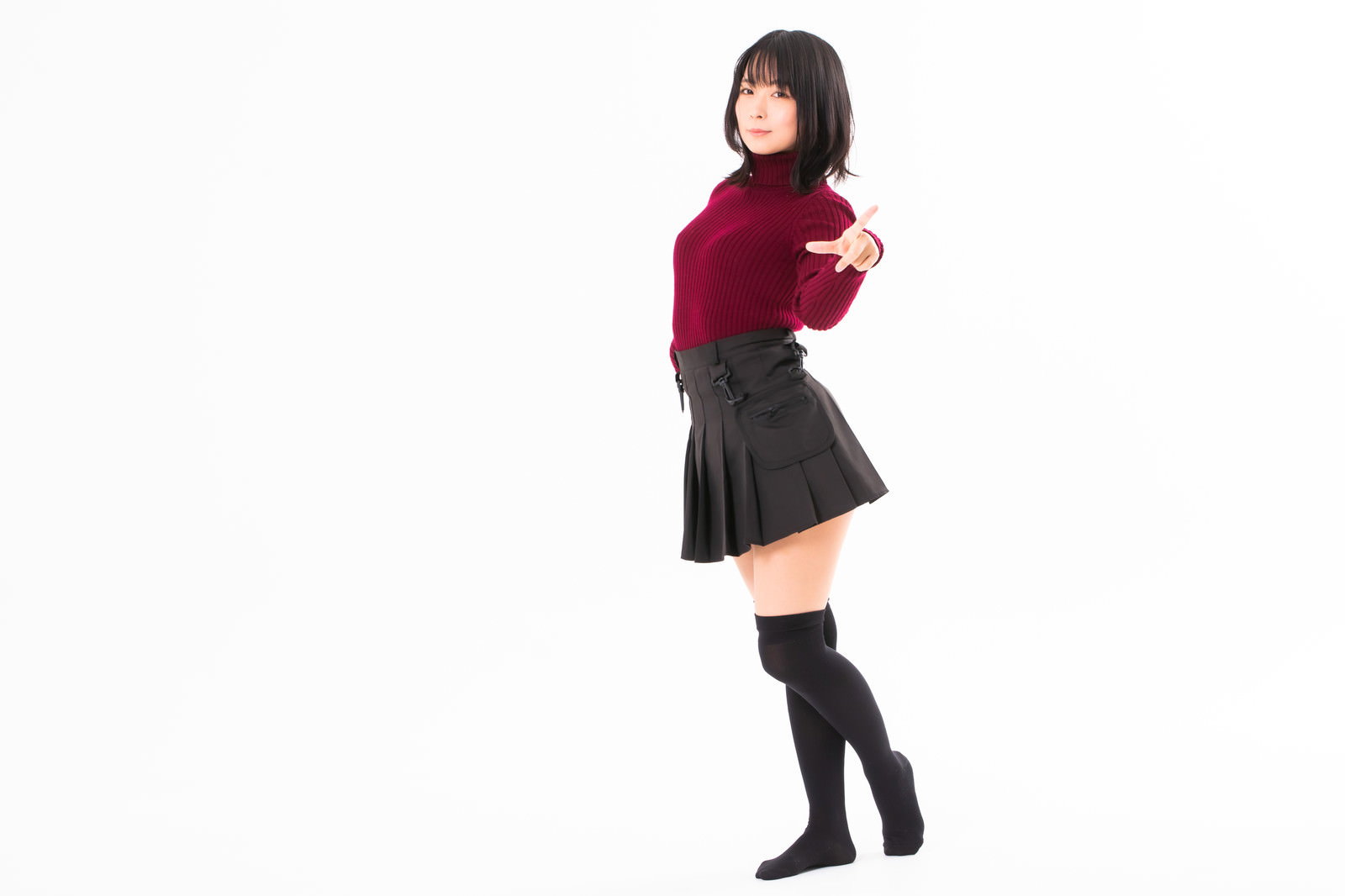 赤いセーターを着た女性が指を差すポーズをとっている写真［モデル：にゃるる］