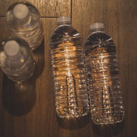 木目調の床に置かれた水のペットボトル、防災備蓄用の写真
