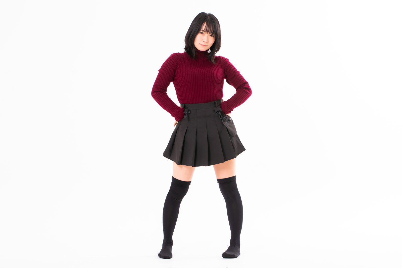 腰に手を当てて自信満々に立つ赤いトップスの女性［モデル：にゃるる］