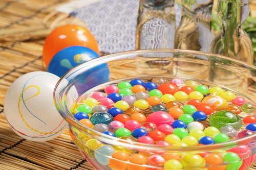 透明なボウルに詰まるカラフルなスーパーボールと水風船