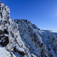 凍り付く日光白根山の岩壁と冬の青空の写真