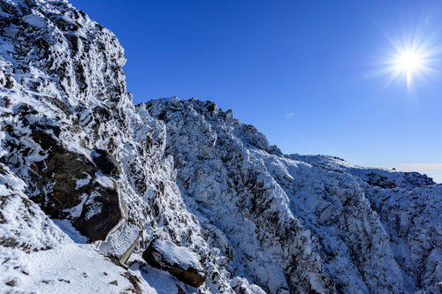 凍り付く日光白根山の岩壁と冬の青空
