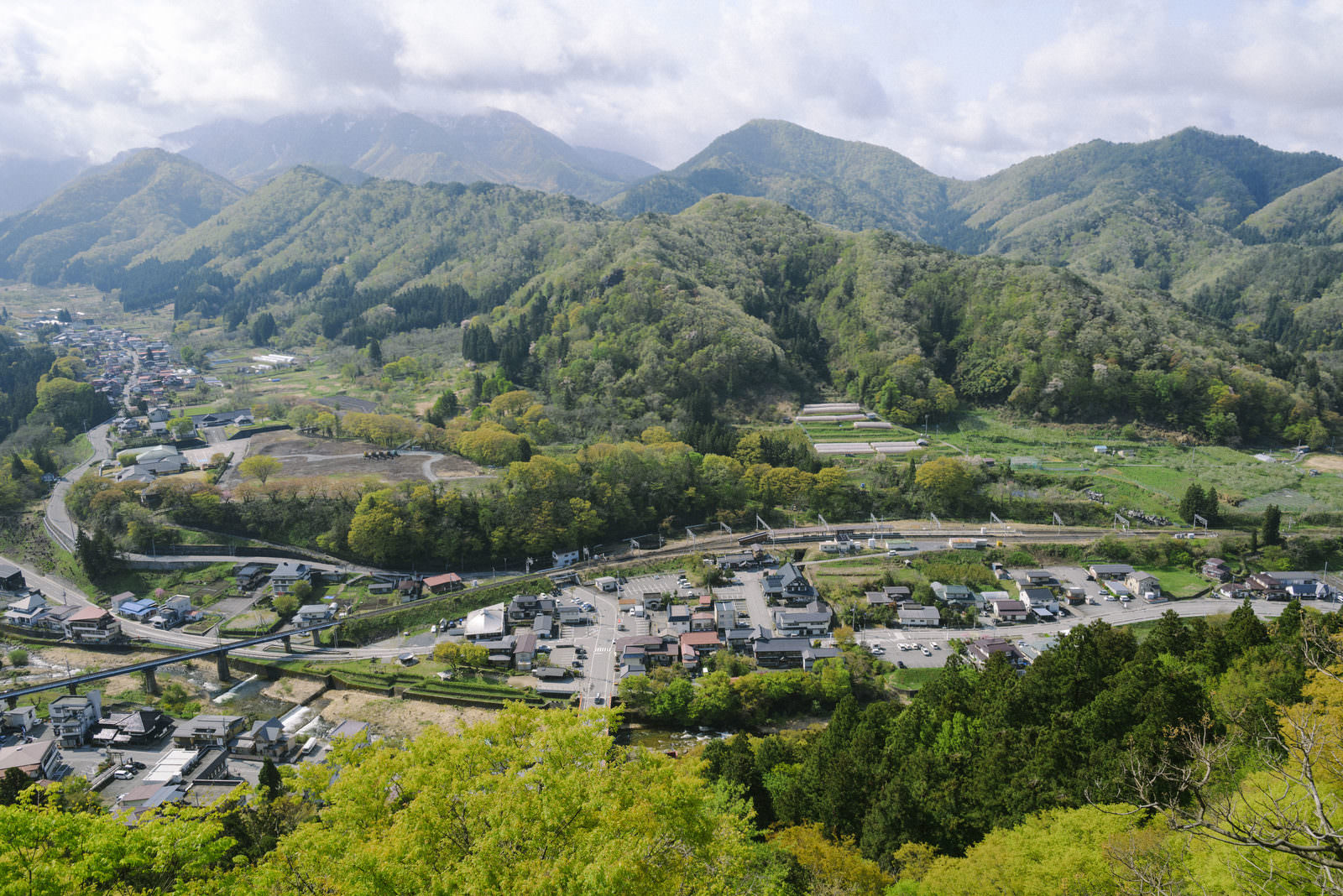 山寺展望台から見下ろす緑豊かな山間の谷に広がる集落と道路の風景