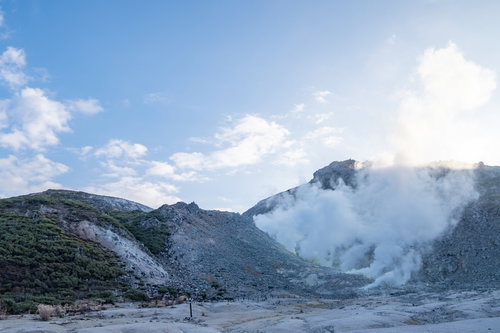 北海道・弟子屈町の活火山アトサヌプリから立ち上る噴煙と青空