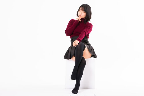 赤いニットで足組みして上から目線の女性、顎に手を当てたポーズ