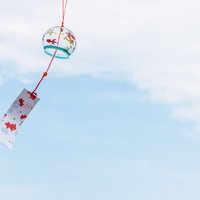 青空を背景に風で揺らぐ小さな風鈴の涼しげな風物詩の写真