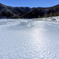 日光白根山麓の凍結した五色沼の冬景色と雪山の写真