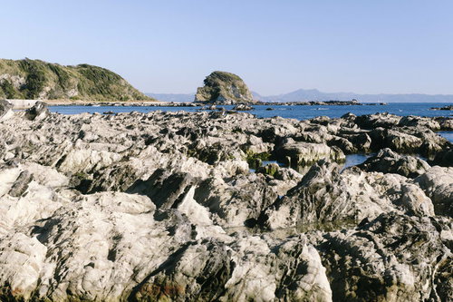 岩礁の道から見る磯場と青い海、ゴツゴツした岩場の海岸風景