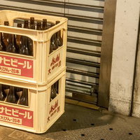 店先に積まれた黄色いケースの空き瓶ビールの写真