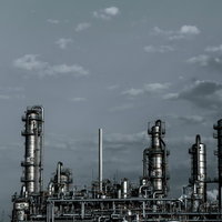 灰色の空と連なる産業用蒸留塔のある化学工場の配管施設の写真