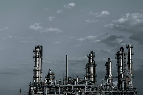 灰色の空と連なる産業用蒸留塔のある化学工場の配管施設