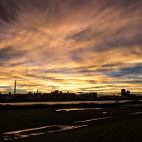 河川沿いの街並みと夕暮れ、通信塔のシルエットの写真