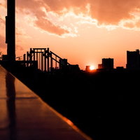 橋と高層ビルのシルエット映える夕焼け空と都市夜景の写真