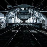 都内の駅のホームから見た線路の奥行きと架線の写真