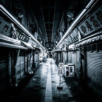 シャッターが閉まった夜間の商店街とアーケードの写真