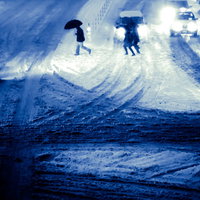 大雪の都心を行き交う人々と夜間の街路風景の写真