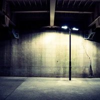 夜間照明がまぶしく照らす不気味な街灯とコンクリート壁の写真