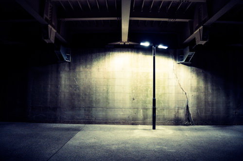 夜間照明がまぶしく照らす不気味な街灯とコンクリート壁