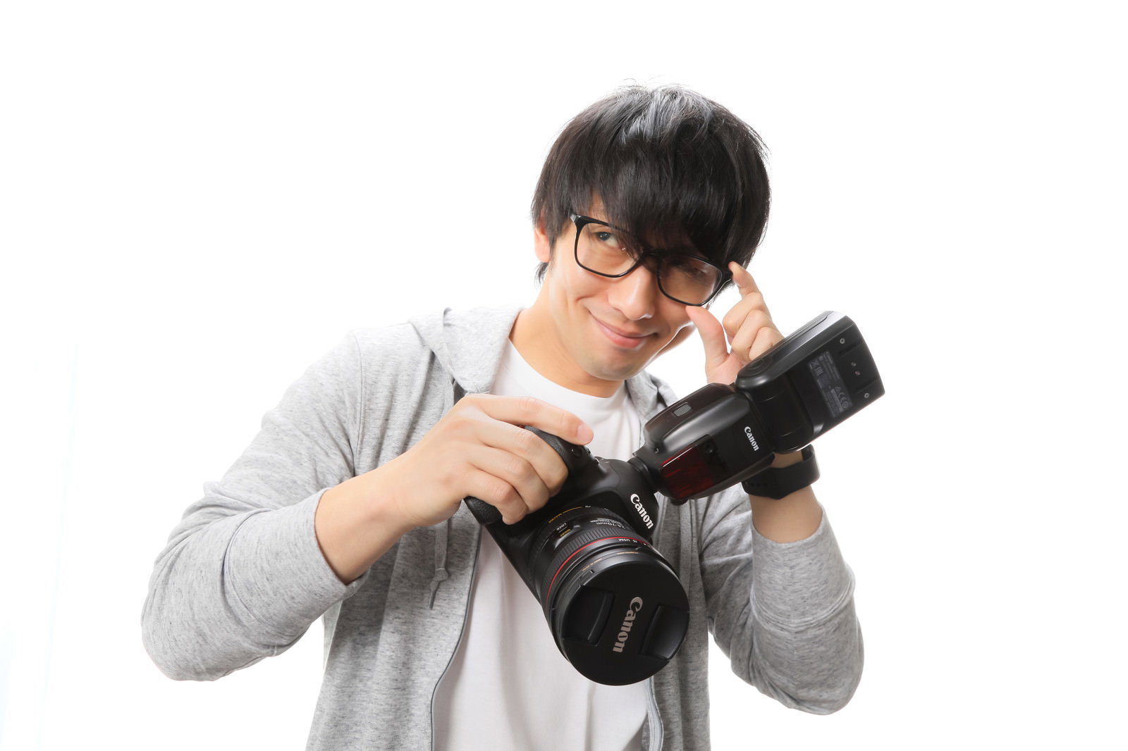 一眼レフカメラを両手で構えて撮影姿勢をとる眼鏡をかけた男性［モデル：大川竜弥］