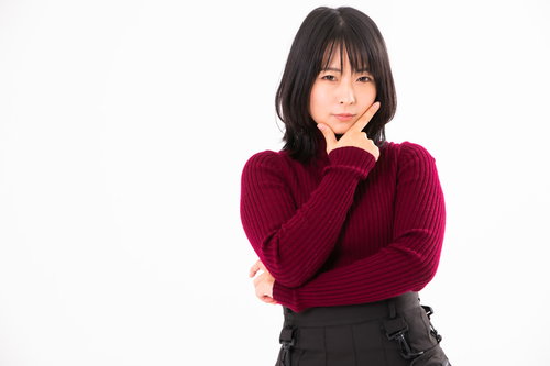 顎を人差し指と親指で挟む考える仕草をする女性