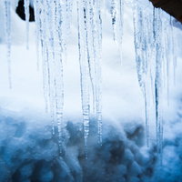 軒下に付いた透明な氷柱と青空、白い雲の冬景色の写真
