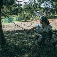 木陰で大弓を張る半着姿の野盗・山賊の男性の写真