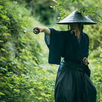 森の中で日本刀を抜く網代笠を被った用心棒の侍の写真