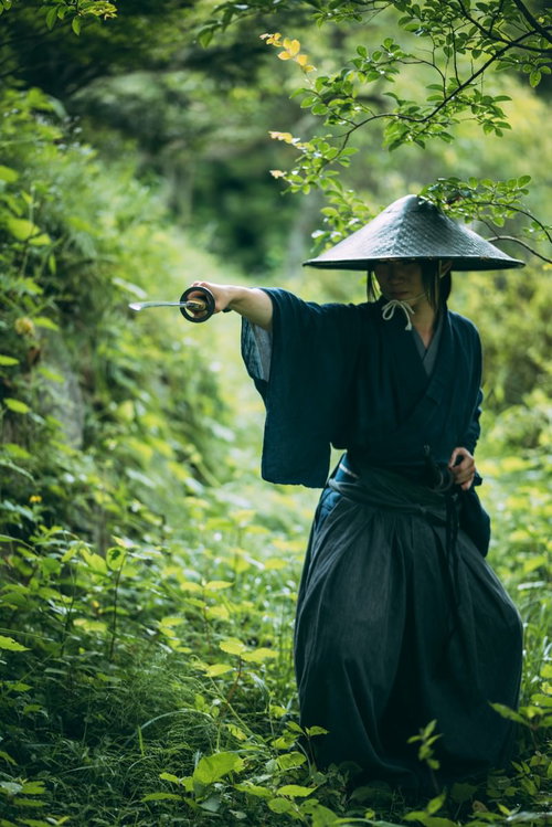 森の中で日本刀を抜く網代笠を被った用心棒の侍