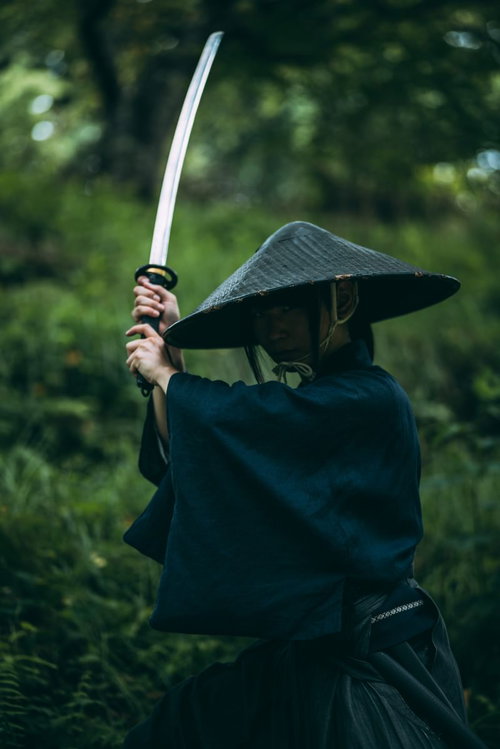 深い笠を被り刀を上段に構える用心棒の男性
