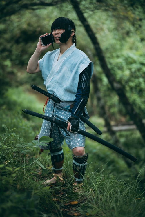 スマートフォンで通話中の野盗の和装姿の男性役者