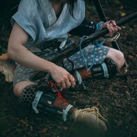 薄暗い森で地面に座り込み火縄銃を握りしめる野盗の男性の写真