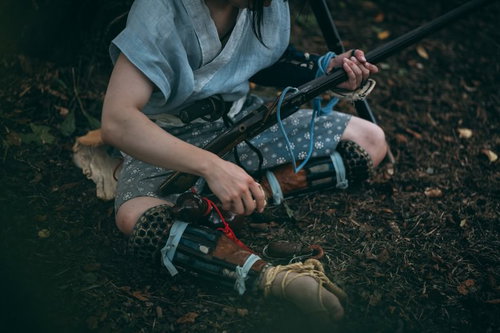 薄暗い森で地面に座り込み火縄銃を握りしめる野盗の男性