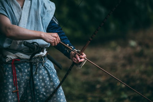 大弓を引く山賊の手元、弓矢を構えて狙いを定める