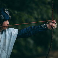 白い着物姿で大きく弓を引く野盗の男性の写真