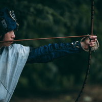 森の中で大弓を引く野盗の腕の写真