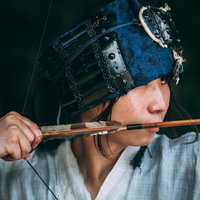 青紋の甲冑に身を包み弓を引く野盗の横顔姿の写真