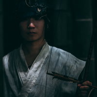 暗がりで大弓を持ち静かに佇む追いはぎの男性の写真